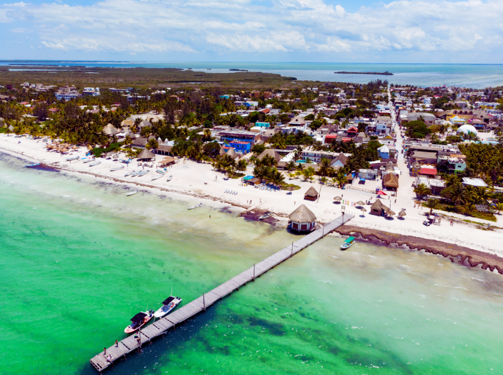Aerial view of Holbox Island in Mexico showcasing its pristine beach, turquoise waters, and charming coastal village.