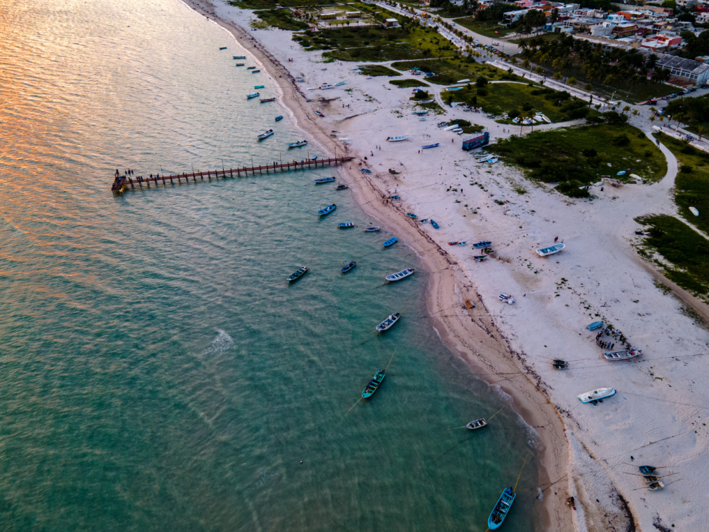 Aerial view of a beachfront with white sand and the sea at dusk.