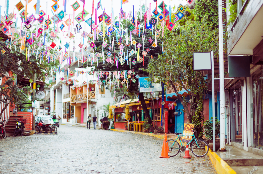 Colorful street in Sayulita, Mexico, with vibrant decorations hanging above and charming shops along the cobblestone road.