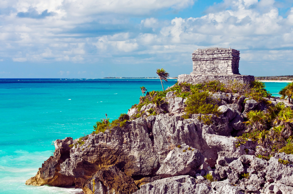 Ancient Mayan Ruins on top of a hill looking out the turquoise waters of the Caribbean.